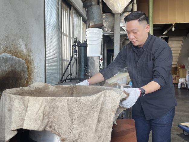 高市青年局長張以理親自操作萃取麻油前的炊蒸步驟，體驗百年品牌所堅持的職人精神。
