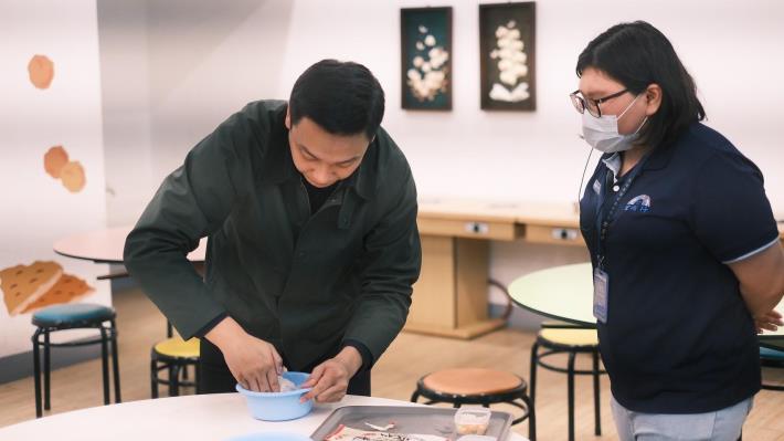 青年局長張以理（左）拜訪宏裕行，除肯定企業提供實習機會讓青年磨練技能，也體驗手作花枝丸的流程與技巧。 （高雄市政府青年局提供）