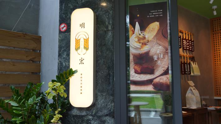 圖4. 「明宏拔絲地瓜」店面以溫潤色調與簡約設計呈現，結合招牌與甜點形象海報，展現從夜市起家到精緻品牌的轉型歷程。(業者提供).JPG