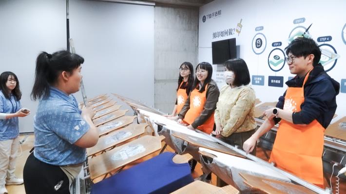 參與「大港青年實習媒合計畫」的郭姓實習生（右二），引導青年局團隊示範手作T-shirt流程。