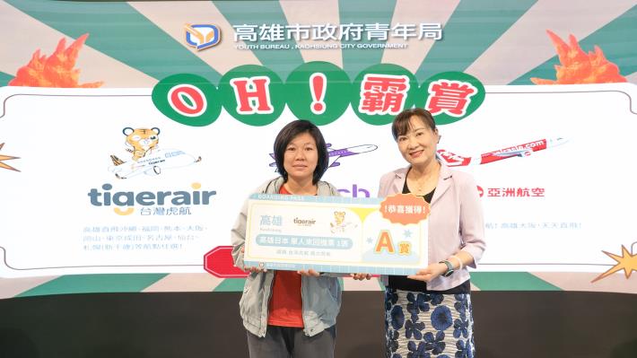 圖說5.參與「OH!霸賞」線上加碼抽幸運抽中台灣虎航高雄直飛日本航點任選來回機票的民眾（左），日前前往青年局由主任秘書吳淑慧（右）頒贈機票大獎並合影留念。