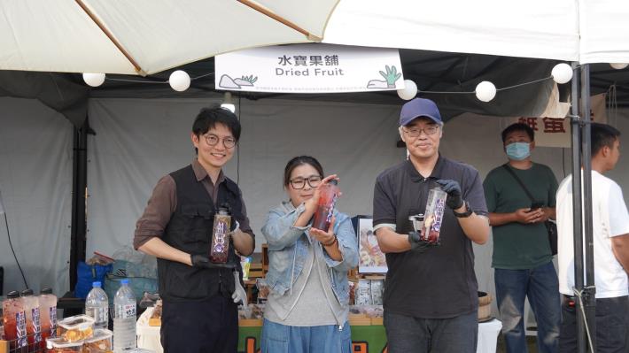 圖2. 青年局長林楷軒（左）昨（3）日陪同高雄市副市長李懷仁（右）訪視「掠食者市集」，除在青創品牌「水寶果舖」體驗沖泡茶飲，還與業者及其推出的限定商品小恐龍香蕉乾合影，展現市府支持青創發展的決心。