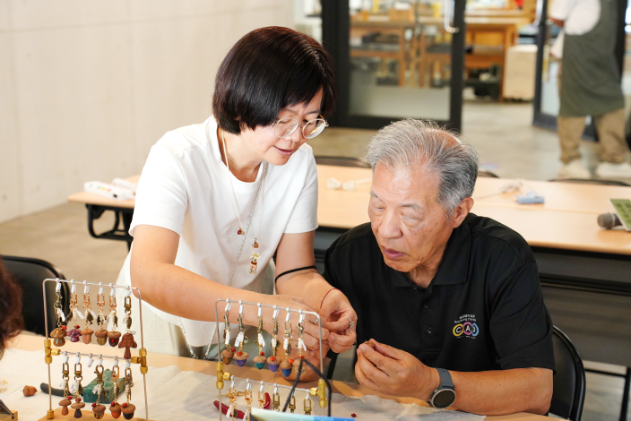 圖說3.樹德科技大學朱元祥董事長（右）於「穩定木橡實種子吊飾DIY」體驗中親手製作自然風吊飾，感受廢材轉化為工藝品的永續創作樂趣。 - 複製