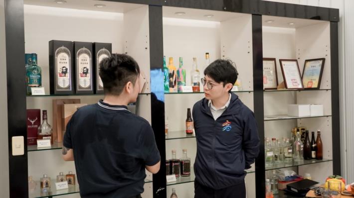 圖1：亞耕酒業總經理江岳樓（左）向高雄市政府青年局長林楷軒（右）介紹企業品牌特色，分享如何結合高雄農產（芒果、荔枝、芭樂）研發不同的風味酒。