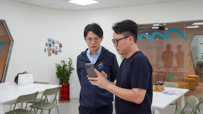 圖5. 地球星創辦人曾澤民（右）操作手機，向青年局長林楷軒（左）解說生成式AI影像應用。